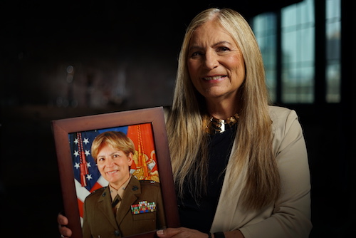 Retired Major General Angela Salinas, a veteran of the U.S. Marine Corps. holding photo of younger self in military dress