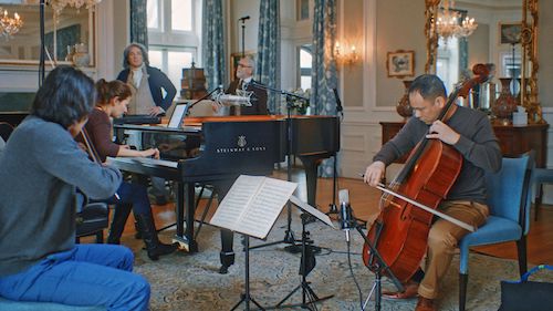Three musicians being watched by actors dressed as Beethoven and Freud