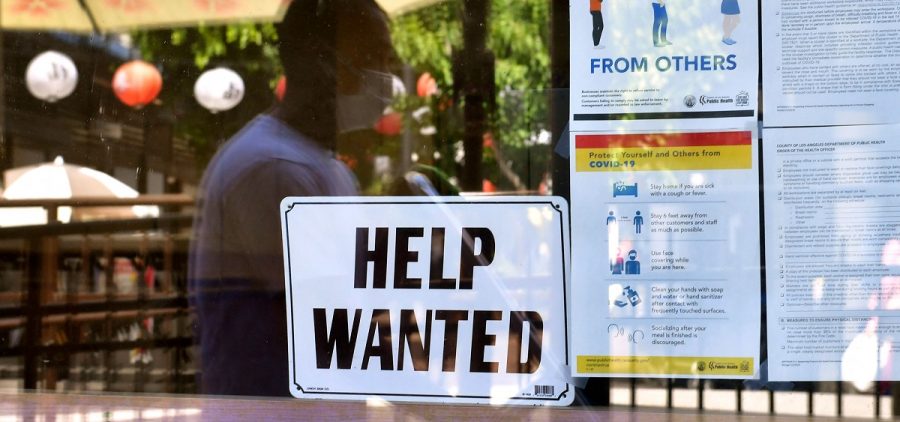 A 'Help Wanted' sign is posted beside Coronavirus safety guidelines in front of a restaurant in Los Angeles, California on May 28, 2021.
