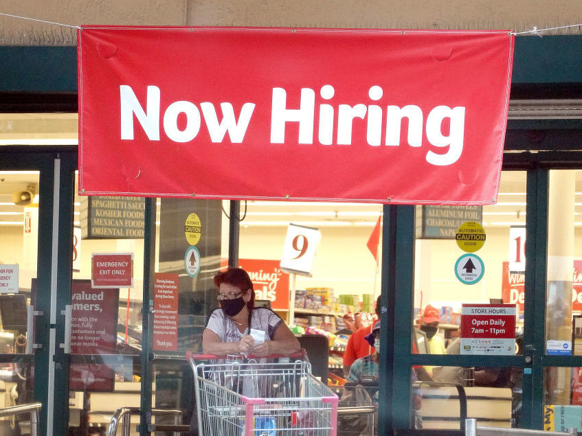 A Now Hiring sign hangs near the entrance to a Winn-Dixie Supermarket in Hallandale, Florida.