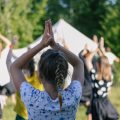 Group of children doing morning exercises hands up yoga sport outdoors in nature in summer camp