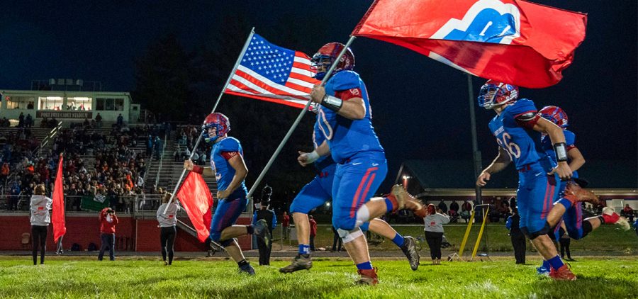 Fort Frye player running with american flag and team flag