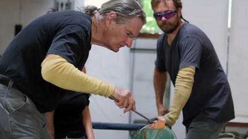 two men working on a glass blowing project