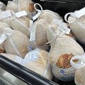 Frozen turkeys sit in a refrigerated case inside a grocery store