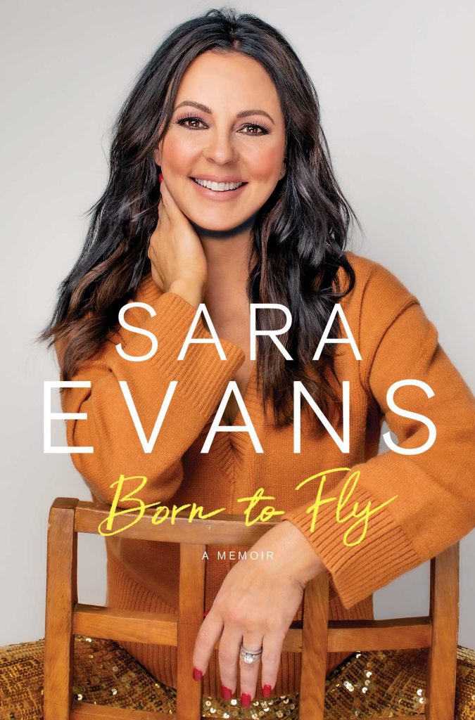 The cover of Sara Evan's "Born to Fly" memoir. Sarah is wearing a sweater and is sitting backwards on a wooden chair.