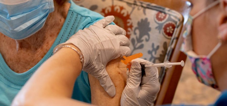 A health care worker administers a third dose of the Pfizer-BioNTech COVID-19 vaccine at a senior living facility