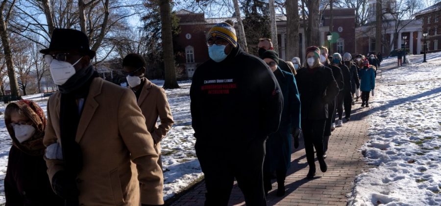 Community members walk through college green at Ohio University while participating in the silent march to honor Martin Luther King Jr., in Athens, Ohio, on Saturday, Jan. 22, 2022. [Joseph Scheller | WOUB]