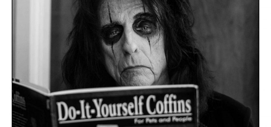 Alice Cooper poses for a promotional photo with a book entitled "Do-It-Yourself Coffins."