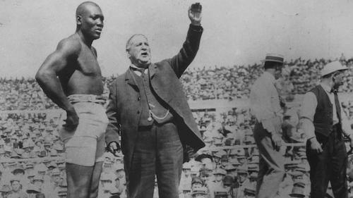 Boxer Jack Johnson in ring being introduced in front of large crowd