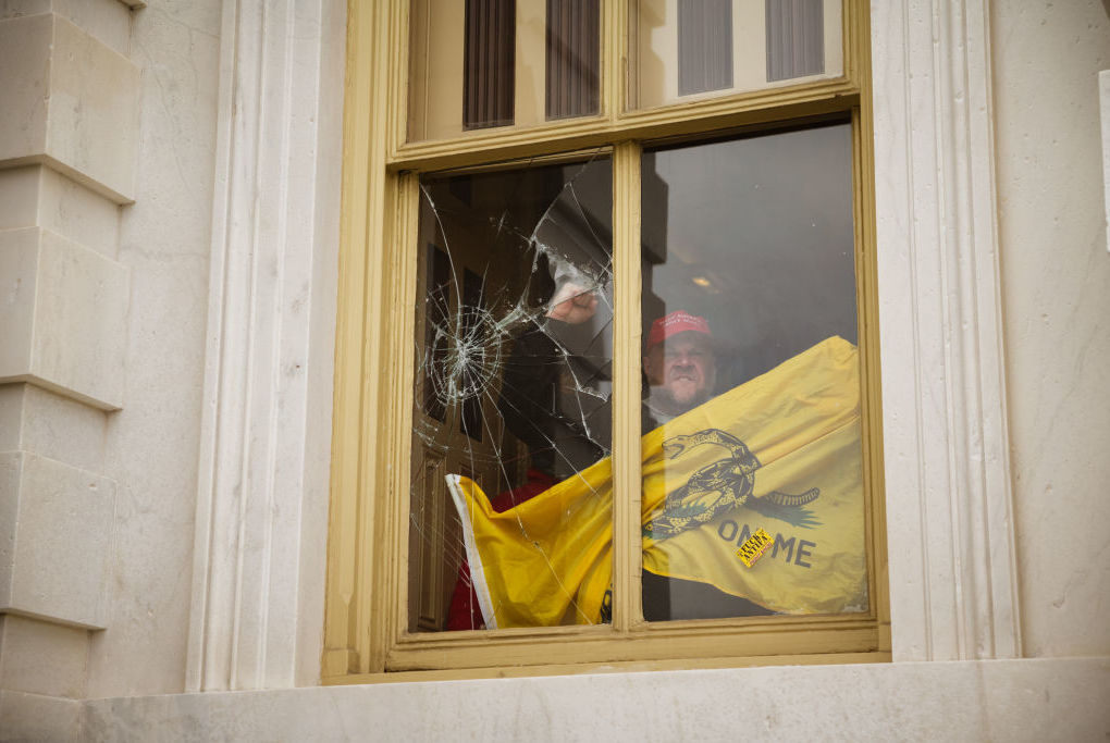 A member of a pro-Trump mob shatters a window with his fist from inside the Capitol building after breaking into it on Jan. 6, 2021.