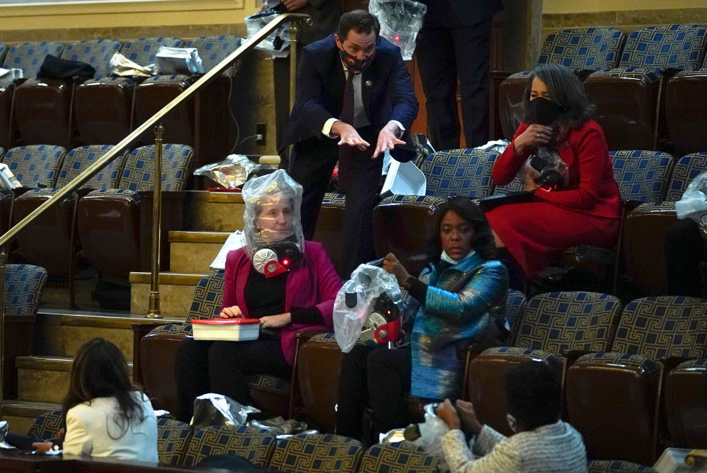 Rep. Jason Crow, D-Colo., directs fellow members of Congress to put on their plastic smoke hood respirators as they are evacuated from the House chamber as protesters attempt to enter on Jan. 6.