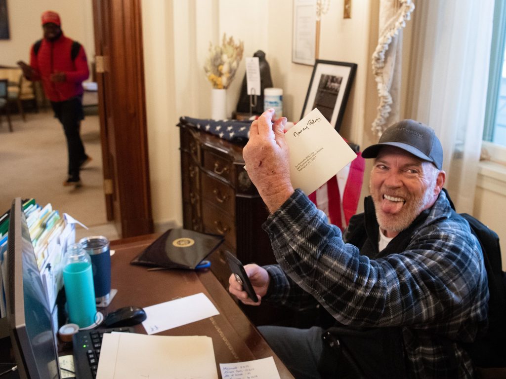 Richard Barnett, a supporter of President Donald Trump, holds a piece of mail as he sits in House Speaker Nancy Pelosi's office after protesters breached the Capitol on Jan. 6, 2021.