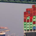 Trucks cross the Vincent Thomas Bridge above a container ship at the Port of Los Angeles on Nov. 30, 2021 in San Pedro, Calif.