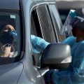 A health care worker conducts a test at a drive-through COVID-19 testing site at Zoo Miami last Wednesday in Miami. In response to the increasing demand for COVID-19 tests, Miami-Dade County opened two new testing sites and expanded hours at the Zoo Miami testing location.