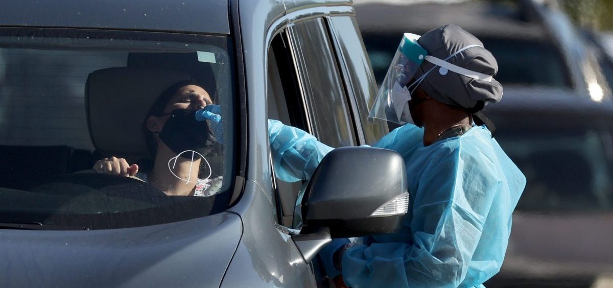 A health care worker conducts a test at a drive-through COVID-19 testing site at Zoo Miami last Wednesday in Miami. In response to the increasing demand for COVID-19 tests, Miami-Dade County opened two new testing sites and expanded hours at the Zoo Miami testing location.