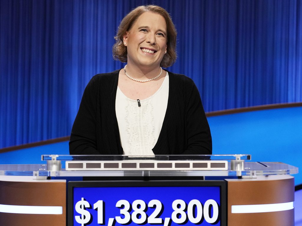 Amy Schneider stands behind a Jeopardy podium with her total winnings displayed It is 1,382,800 dollars