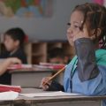 elementary student in classroom thinking with finger on head