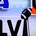 The Super Bowl LVI logo sit in front of a screen that has the Rams logo on the left and the Bengals logo on the right
