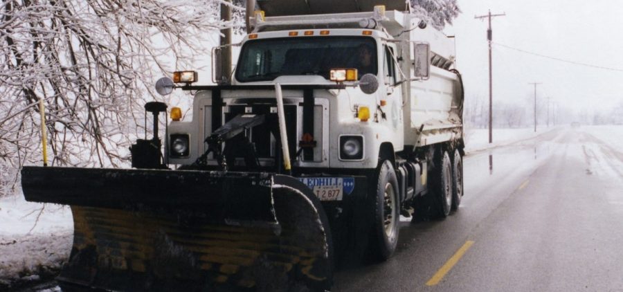 A snow plow works to clear a road