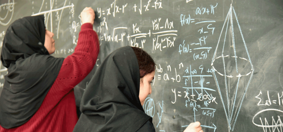 Iranian women working complex math on blackboard