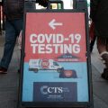 People pass a COVID-19 testing site on a Manhattan street