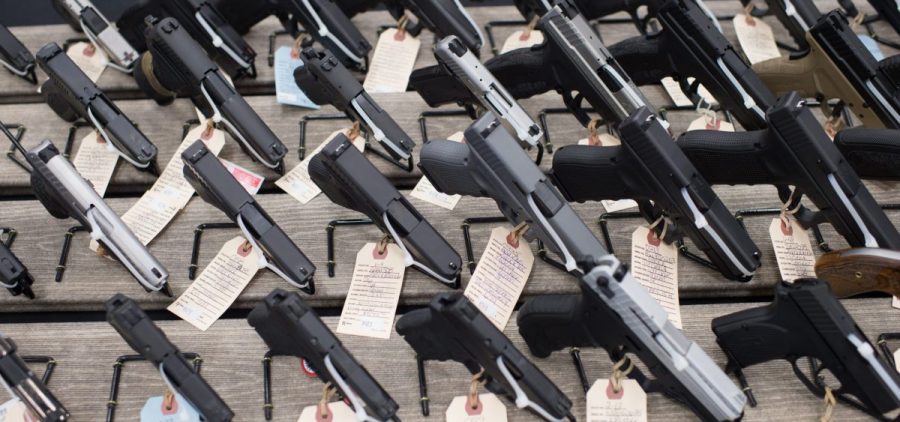 A whole bunch of handguns displayed with tags on them