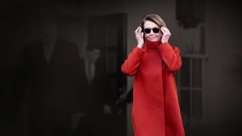 nancy pelosi in red coat putting on sunglasses