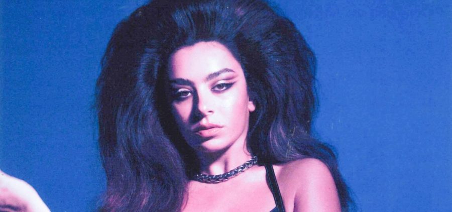 Charli XCX poses for a portrait that is edited to have a very blue or purple filter. The author of this alt text has a color weakness.