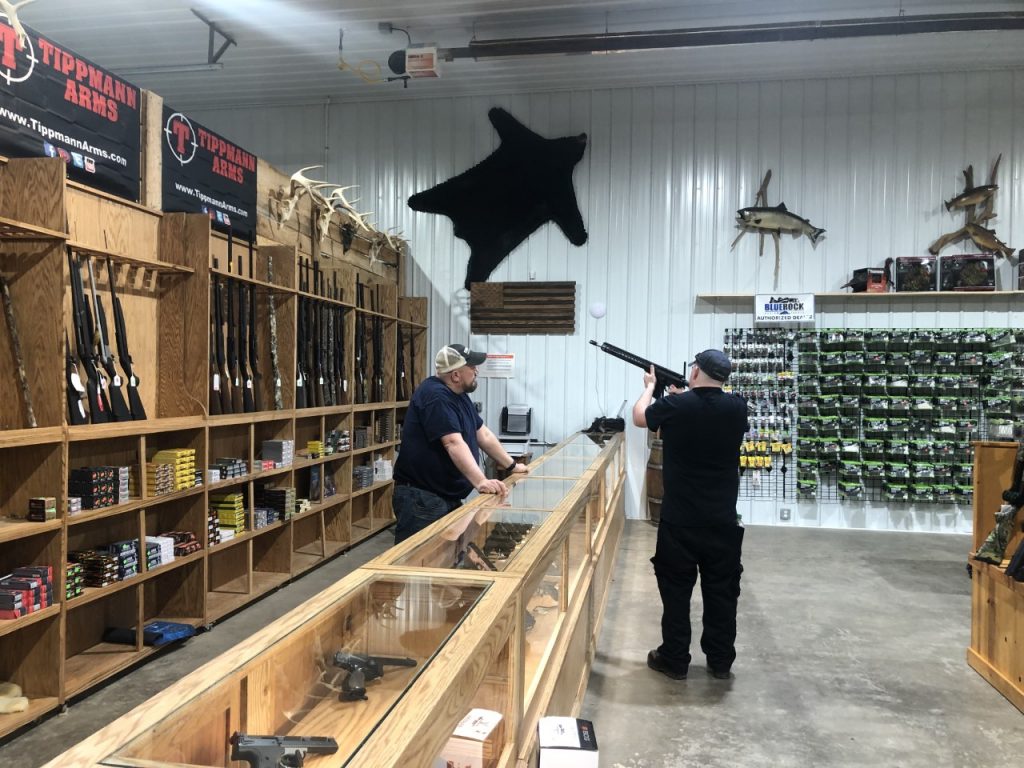 Two men examine a gun at a firearms supply store.