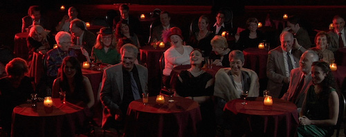 people sitting at small tables in comedy club