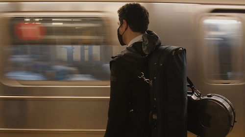 COVID masked man carrying violin waiting on subway