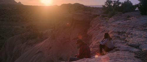 teens sitting on rock overlooking cliff