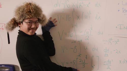 high school student in front of complicated math problem on whiteboard
