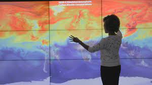 person standing in front of a multicolor climate map