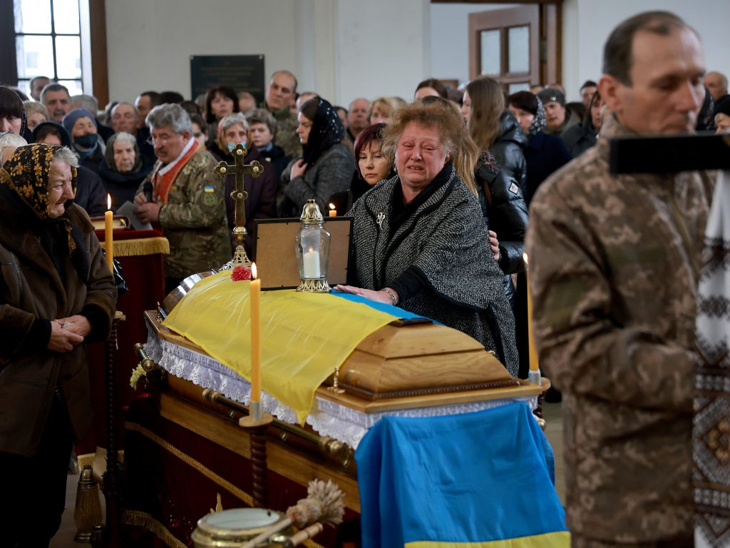 A Ukrainian woman, Maria Korechko, touches the flag-draped casket of her son, Ukrainian soldier Andriy Zagornyakon, during his funeral 