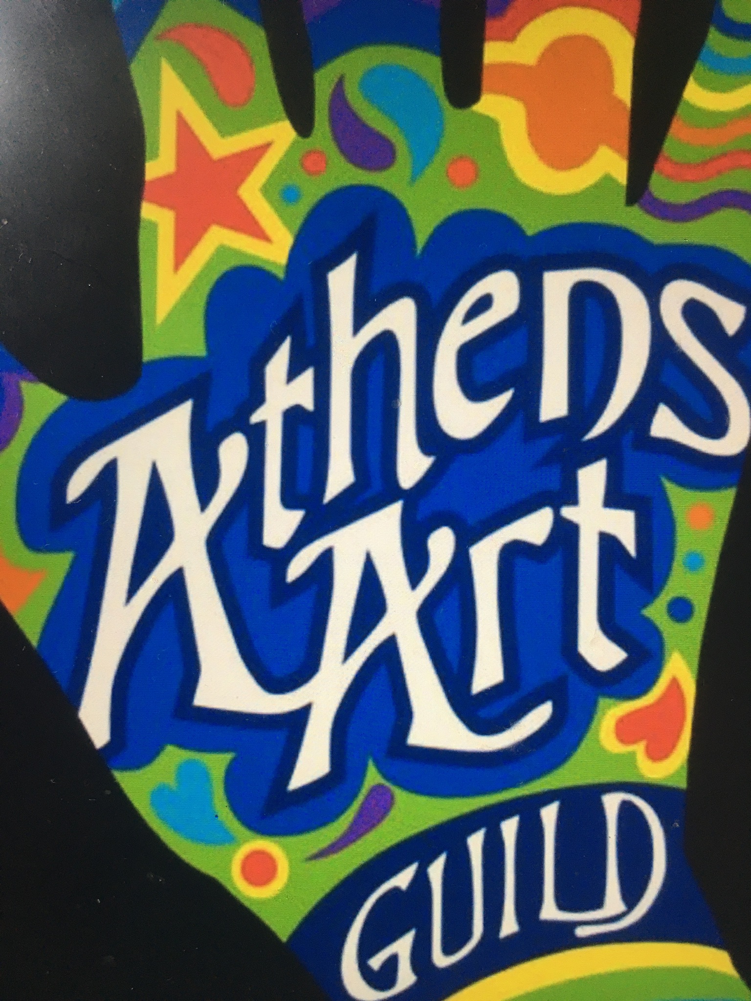 The logo for the Athens Art Guild, white text layered on a colorful graphic of a hand.