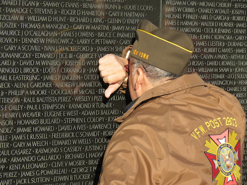 Older soldier weeps against Vietnam Veterans Memorial