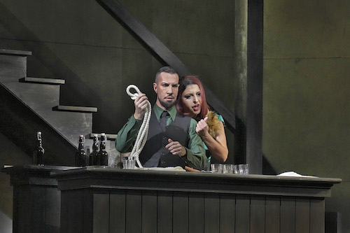 actors in Rigoletto standion behind desk holding rope