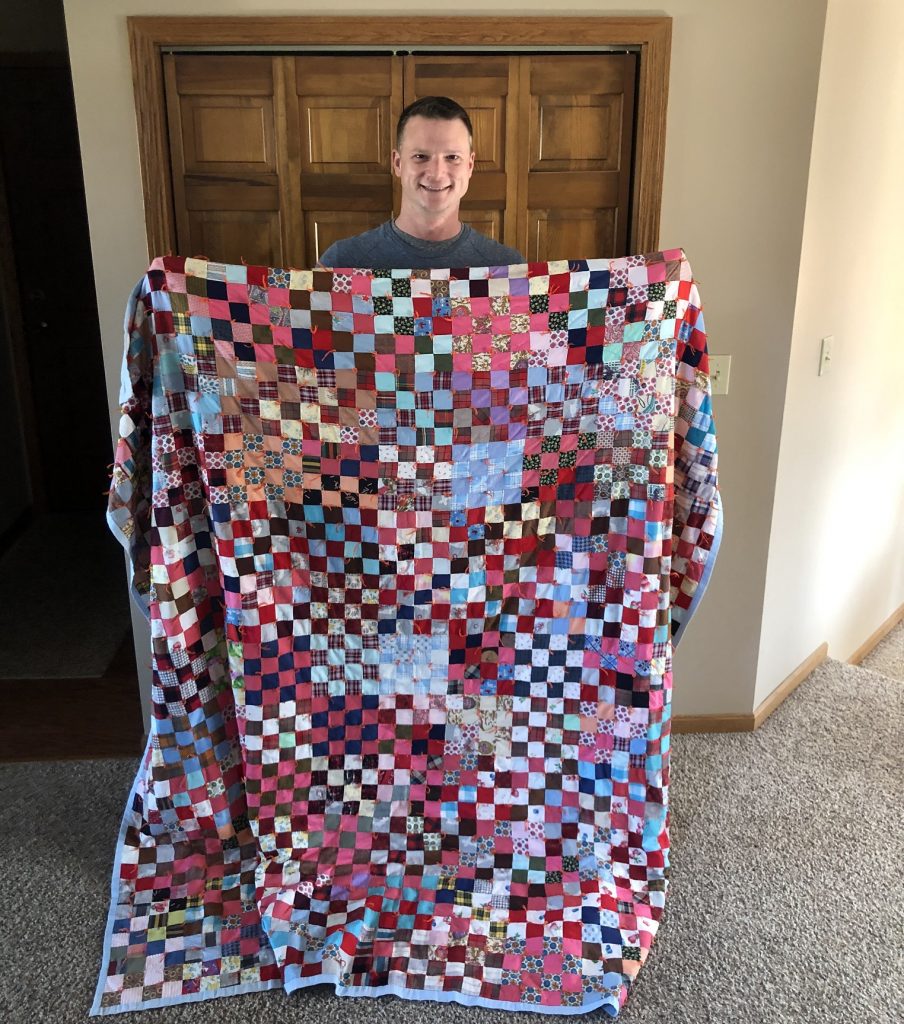 Shane Foster holds up a quilt made by his great-grandmother.