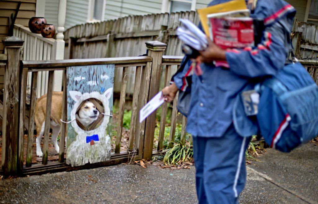 U.S. Postal Service letter carrier of 12 years, Jamesa Euler, encounters a barking a dog while delivering mail in the Cabbagetown neighborhood, Thursday, Feb. 7, 2013, in Atlanta.