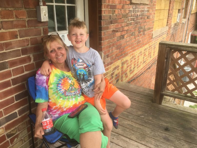 Denise Bates sits on her porch with her grandson in her lap.