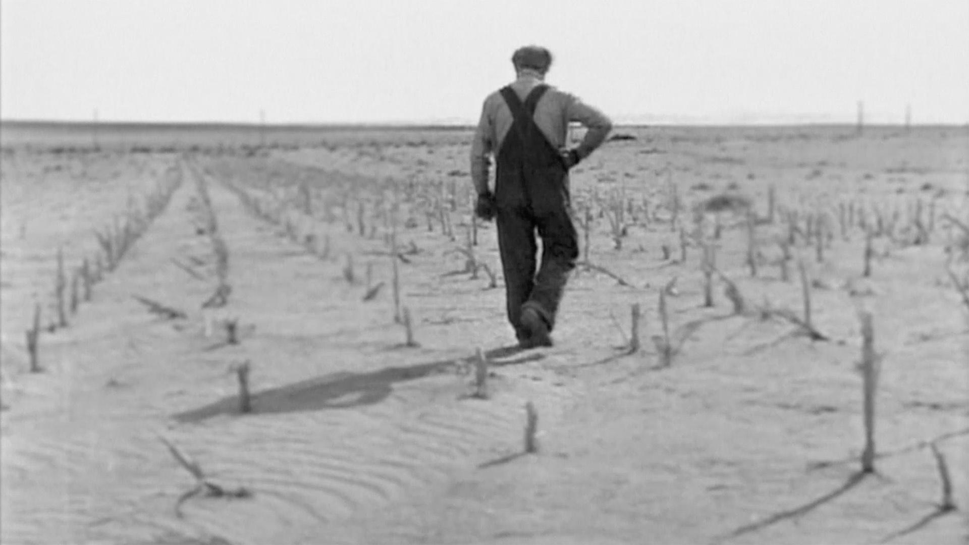 A farmer looking at failed crops during the Dust Bowl