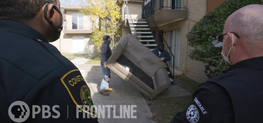two constables watching renters remove a couch from an apartment