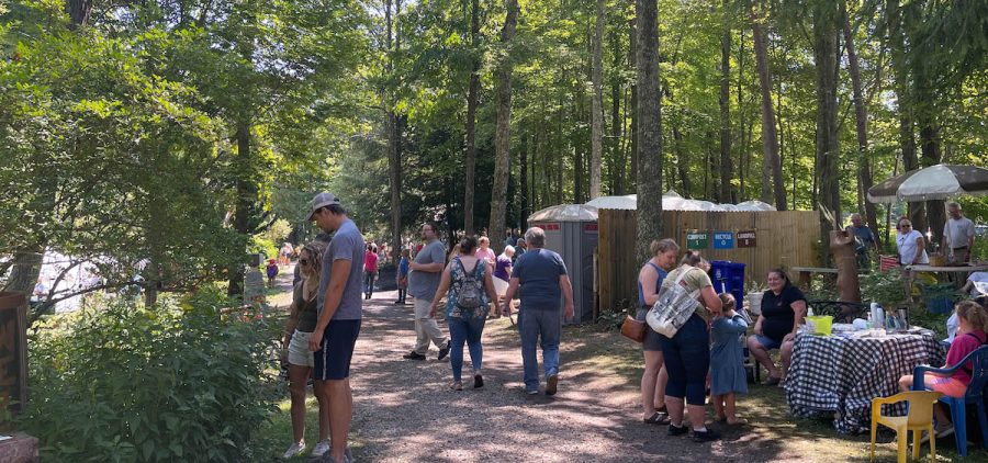 Attendees to the 2022 Lilyfest mill about under a canopy of trees at the Bishop Educational Gardens.
