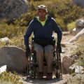 man in wheelchair climbing up mountain trail