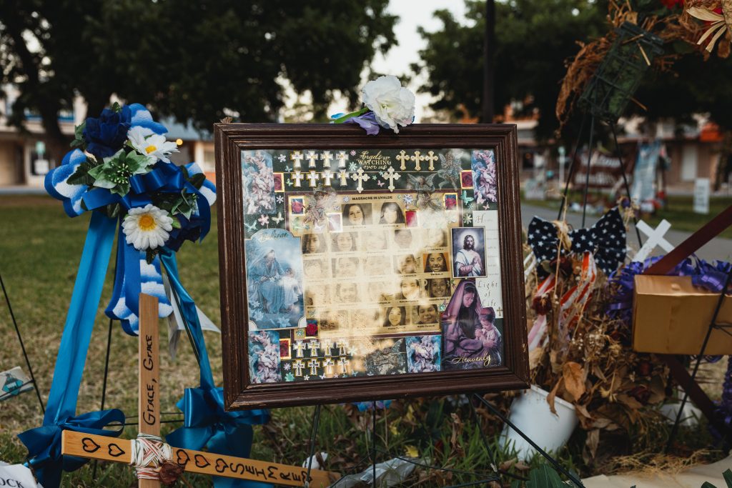 A framed picture is adorned with flowers and crosses at a memorial for the victims of the mass shooting at Robb Elementary School