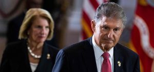 US Sen. Joe Manchin (D-WV) pays respects to US Marine Corp Chief Warrant Officer 4, Hershel Woodrow Woody Williams, laying in honor at the Rotunda of the US Capitol in Washington, DC, on July 14, 2022. US Sen. Shelly Moore Capito (R-WV) stands behind Manchin.