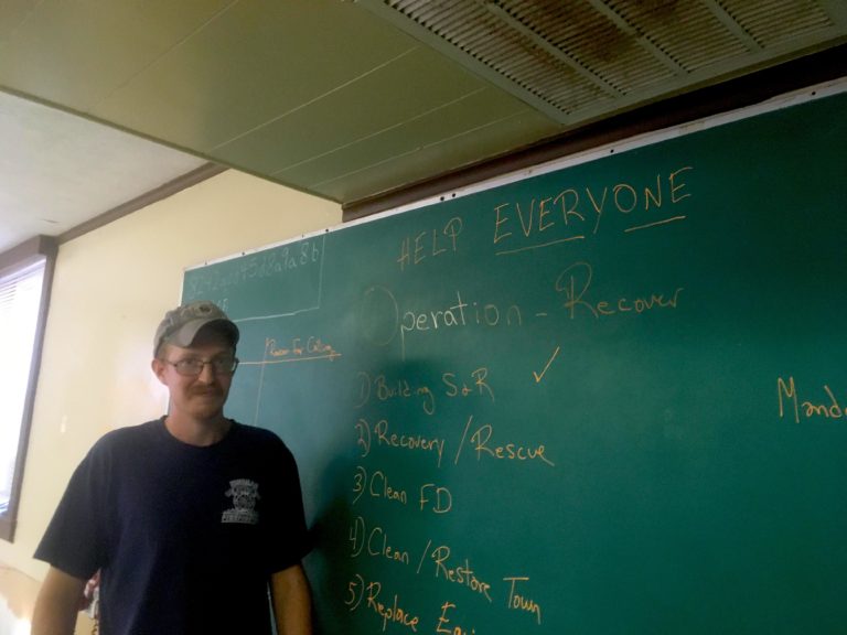 Hindman Fire Chief Preston Hays stands in front of a chalkboard with the rescue plan on it 