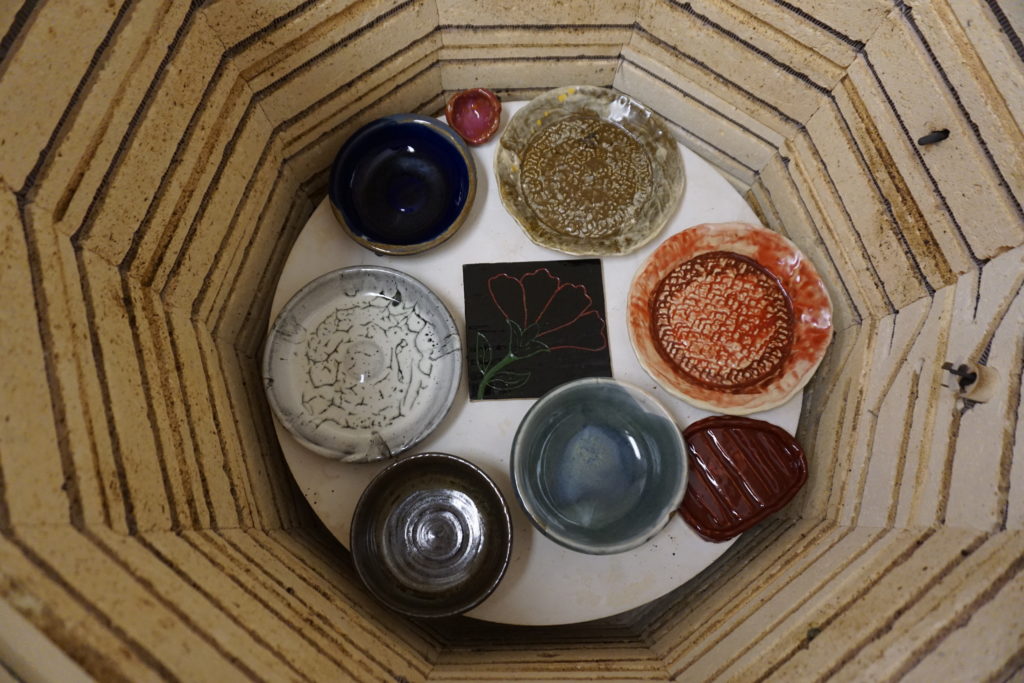 Several pieces of colorful pottery are pictured at the bottom of a kiln.
