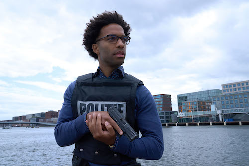 man with police vest on holding handgun